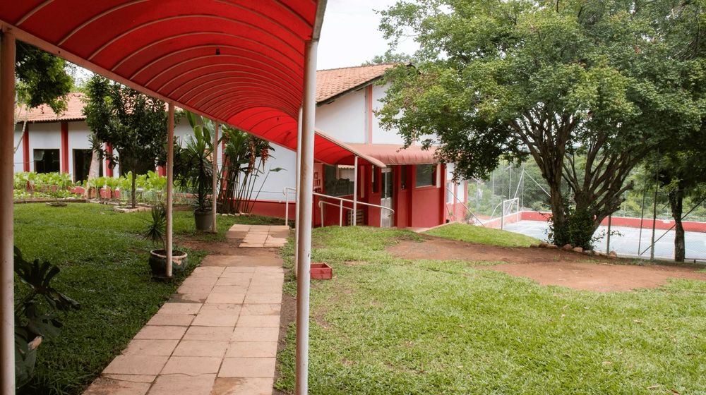 Área externa coberta com jardim e quadra poliesportiva