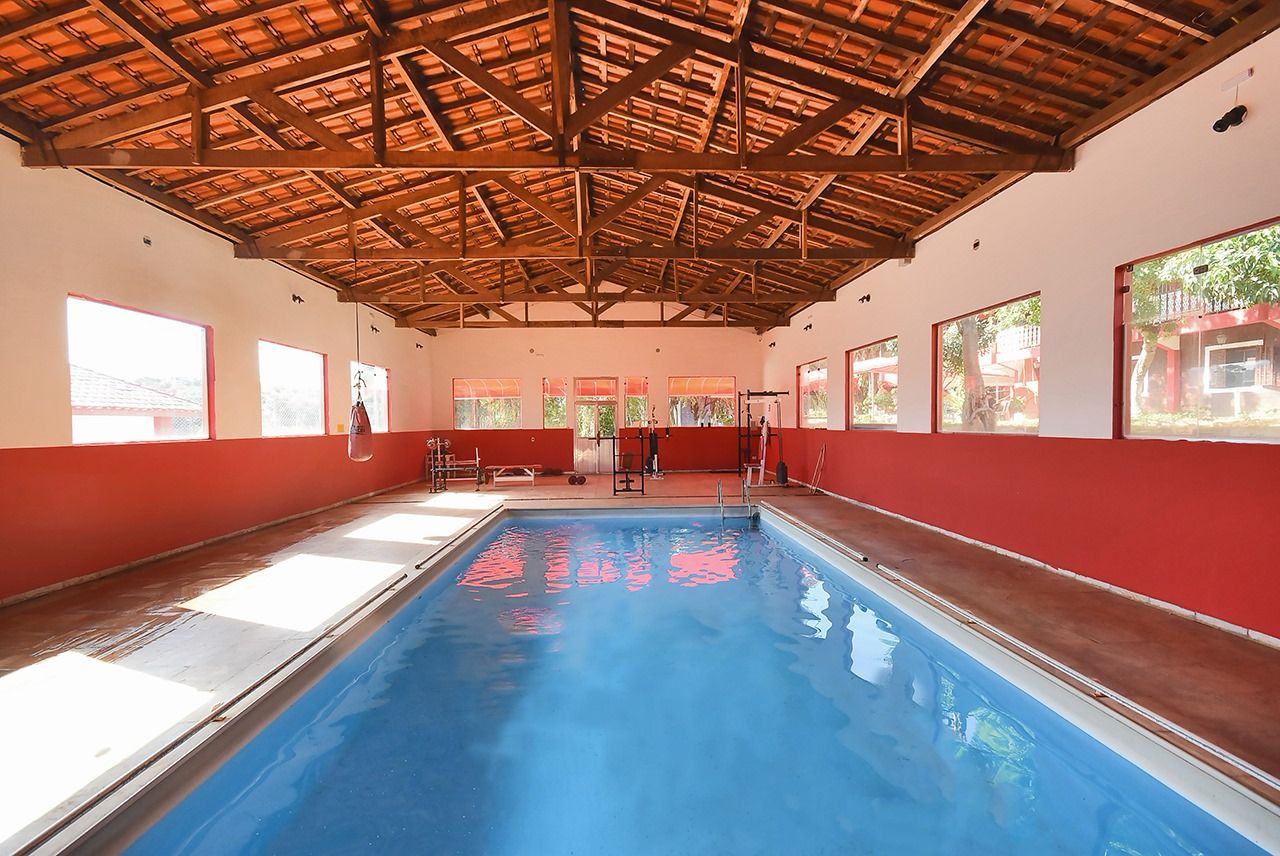Piscina coberta com área de musculação ao fundo